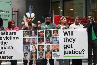 Lundi, huit victimes avaient fait le déplacement, dont certaines en habits traditionnels agitaient devant le tribunal des maracas et interpellaient les passants au mégaphone, réclamant la "justice pour Mariana !". KEYSTONE/EPA/ANDY RAIN